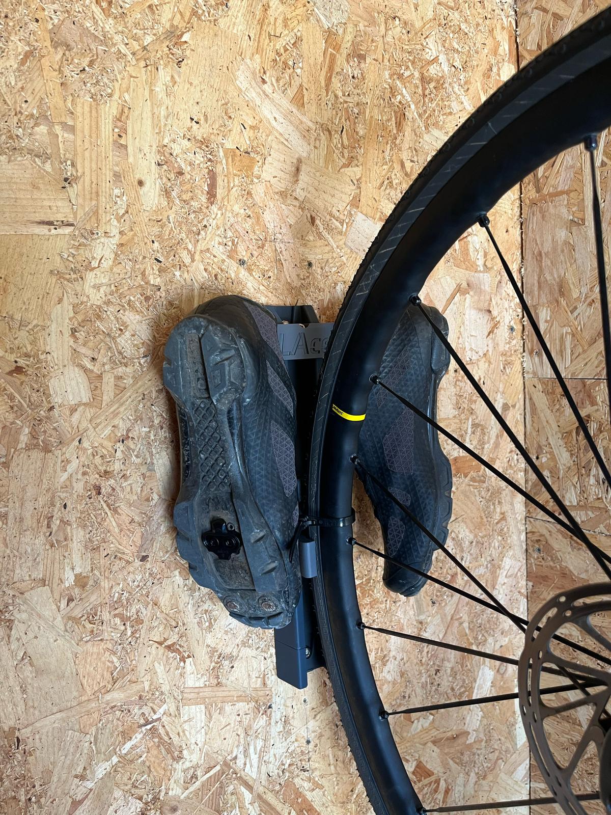 User review photo of the PLAced extended rail kit in use in his home with his bike wheel and cleats showing